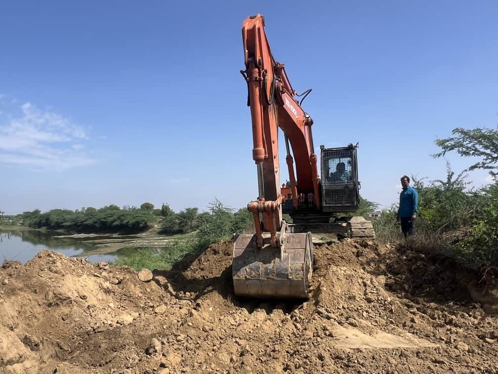 पुल के लिए बन रहे रास्ते के लिए खुदाई करती पोकलैंड मशीन