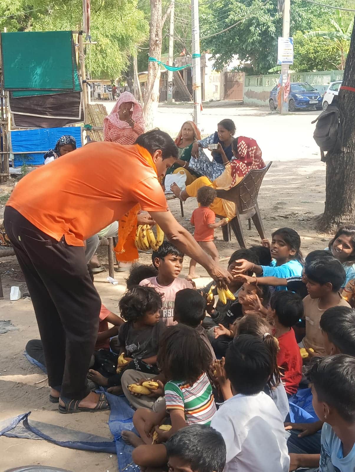 बच्चों को केला वितरित करते कंवर सैनी। स्रोत : संस्था