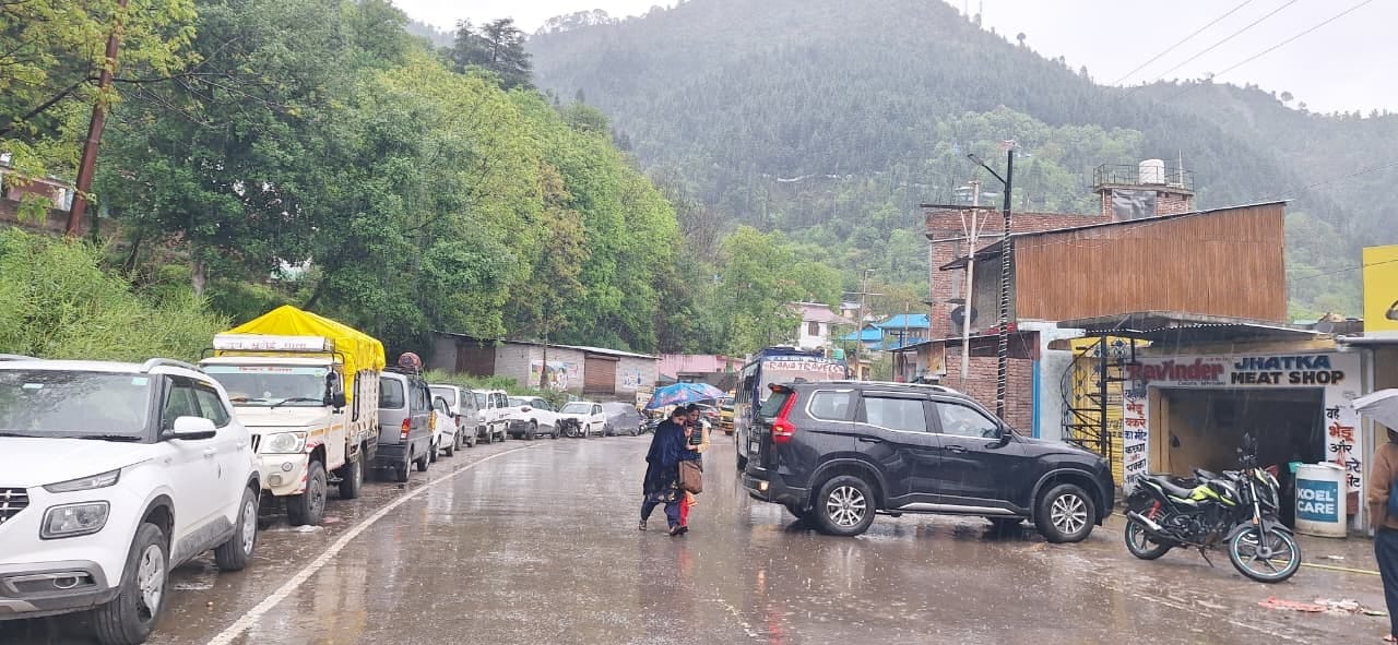 बनी में बारिश के बीच छाता लेकर जाती महिलाएंसंवाद