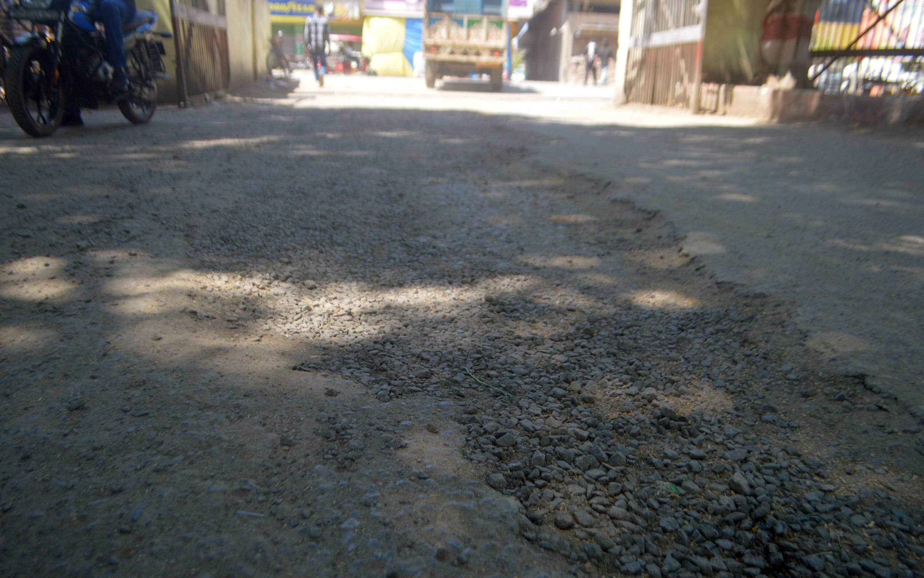 फोटो-01- गल्ला मंडी की मुख्य सड़क पर हुए गड्ढे। संवाद