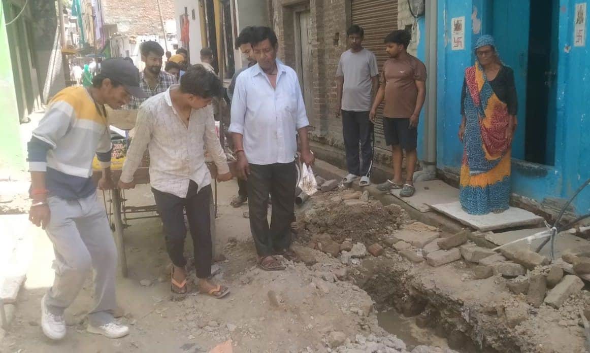 फोटो02कासगंज के मोहल्ला हुल्का में सड़क पर पड़े मलबे के बीच से होकर ठेला लेकर जाता युवक । संव