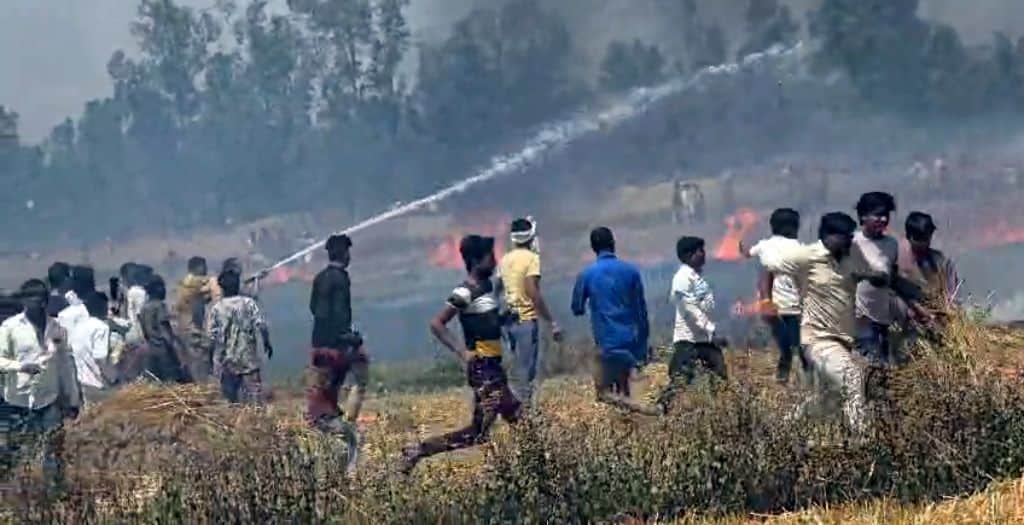 खैराबाद क्षेत्र में जलती गेहूं की फसल व बुझाने का प्रयास करते ग्रामीण।  संवाद