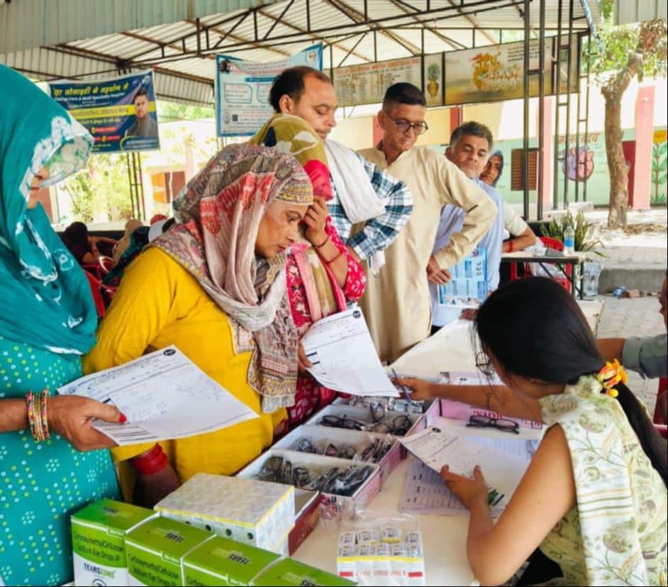 निशुल्क नेत्र जांच शिविर में मरीजों को चश्मा देते देवा वेलफेयर सोसायटी के सदस्य। स्रोत : प्रवक