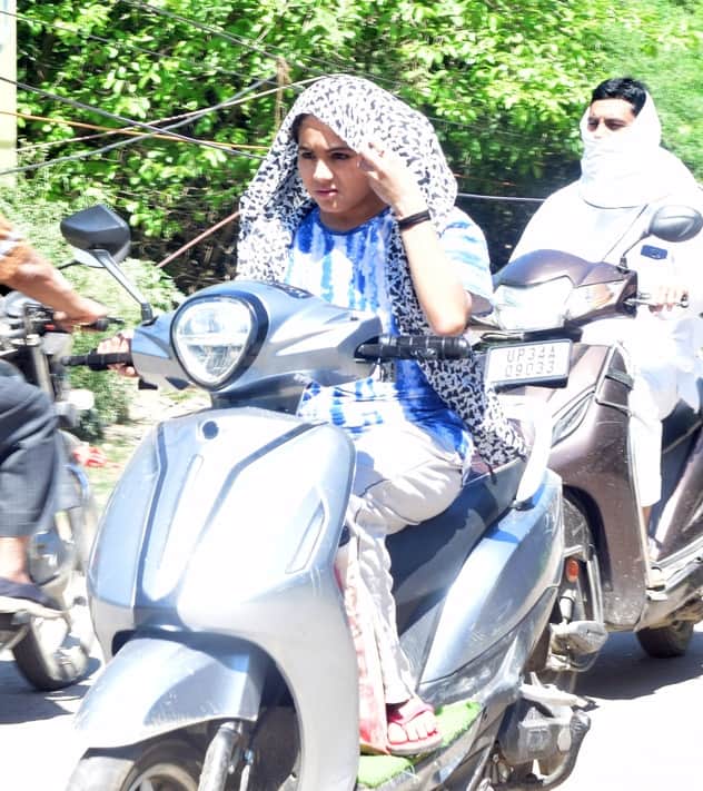 धूप से बचने के लिए रुपट्टे का सहारा लेकर जाती युवती। संवाद