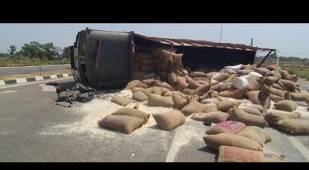 A grain-laden truck overturned after hitting a stone on the highway, two injured.