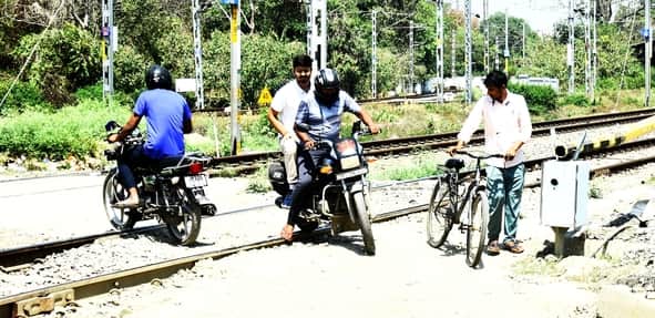 रेलवे क्रॉसिंग को पार करते लोग। 