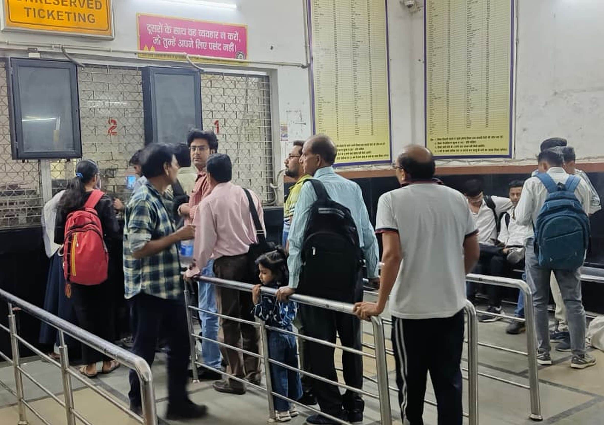 शहर के रेलवे स्टेशन में खिड़की पर टिकट लेने के लिए लगी यात्रियों की भीड़। 