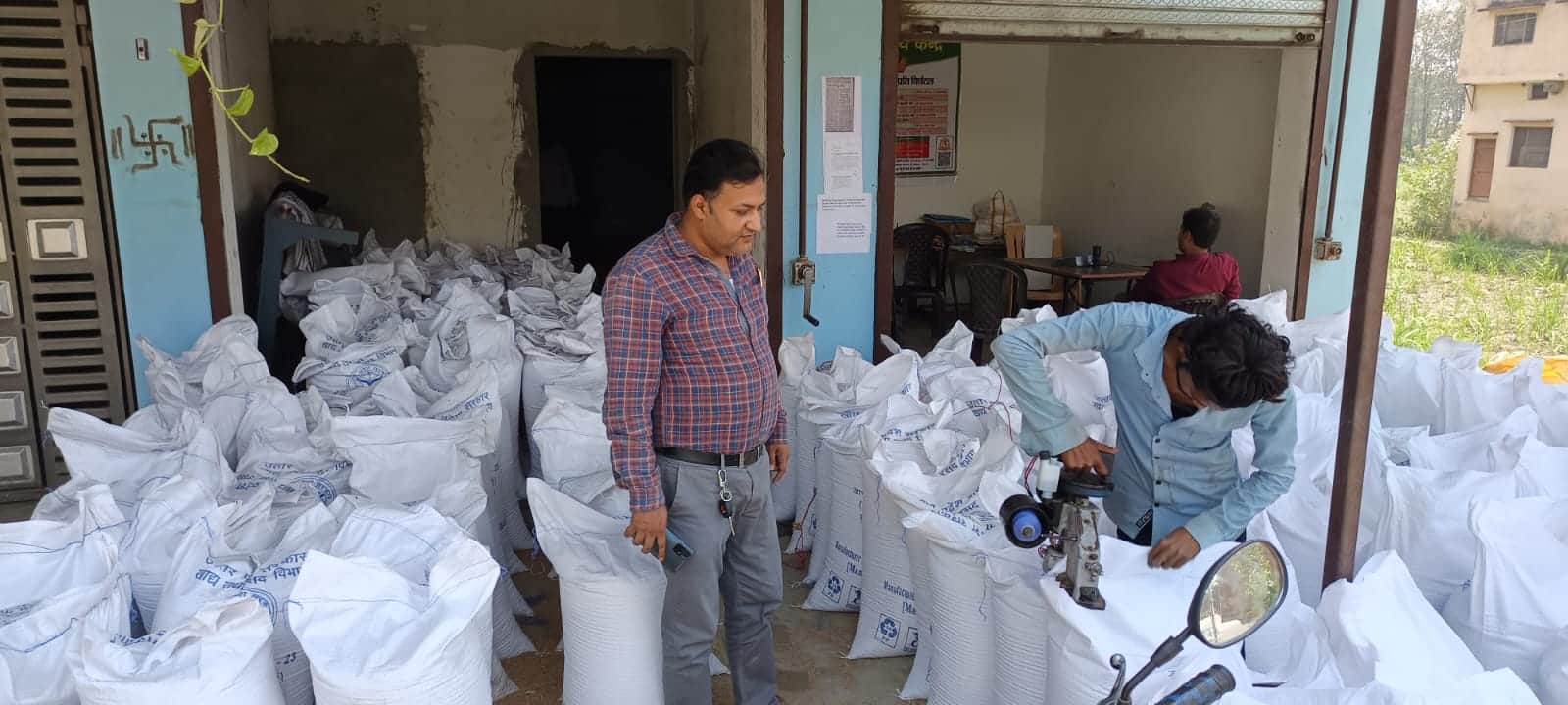 कप्तानगंज गेहूं क्रेय केंद्र पर खरीदारी किए गए गेहूं की बोरी की सिलाई करते  मजदूर।संवाद