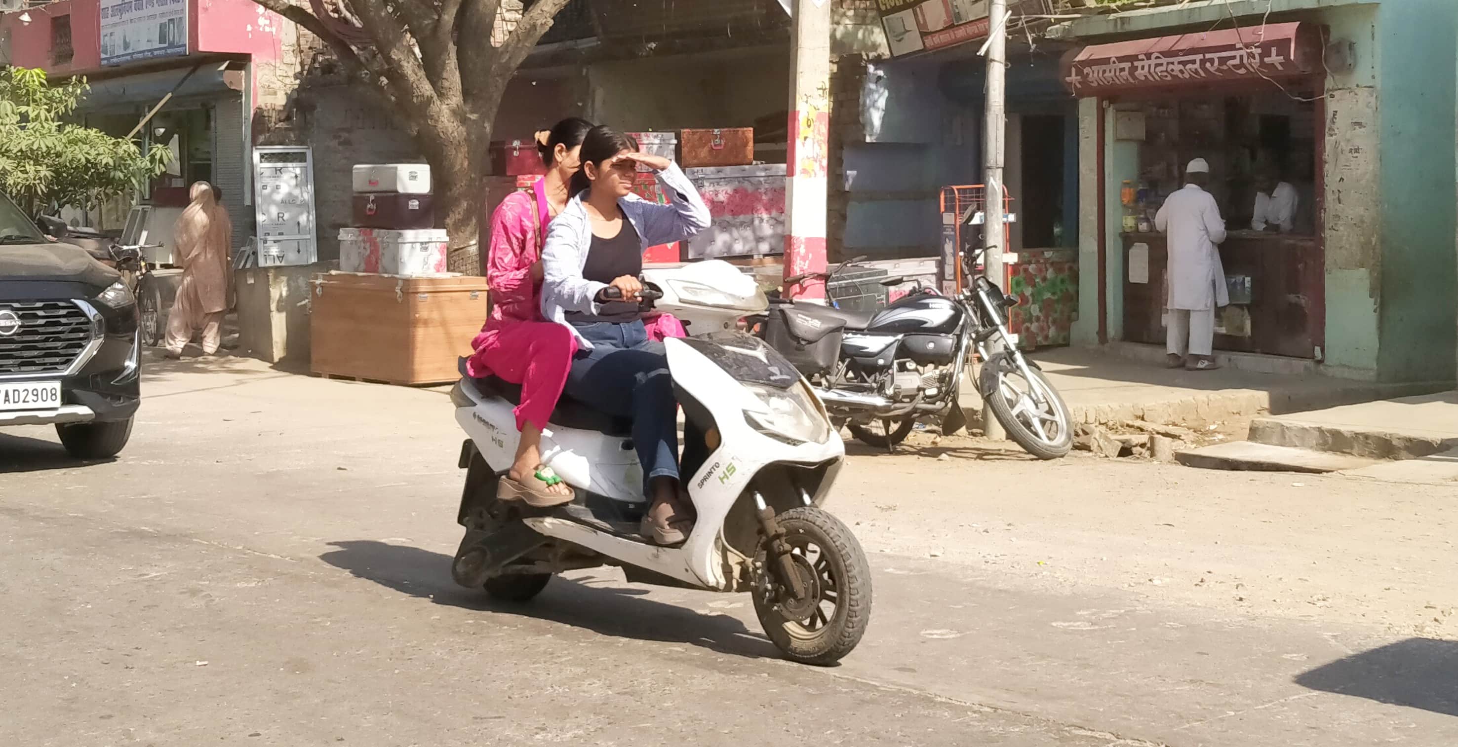 फोटो-8-बलरामपुर के गोंडा रोड पर धूप स बचते हुए स्कूटी से जाती युवतियां ।-संवाद