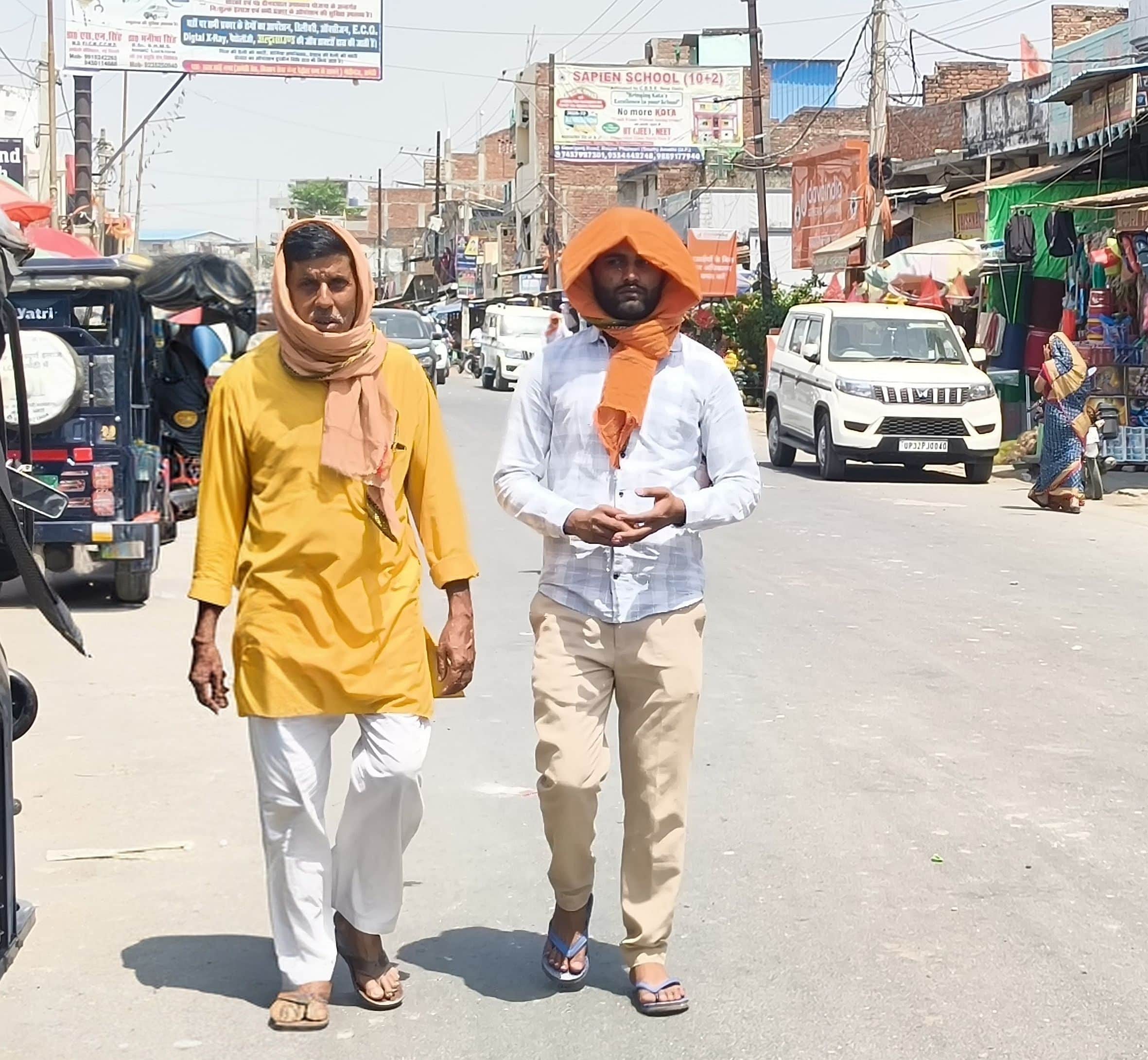 गौरीगंज शहर में धूप से बचाव के लिए गमछे से सिर को ढककर जाते लोग। -संवाद