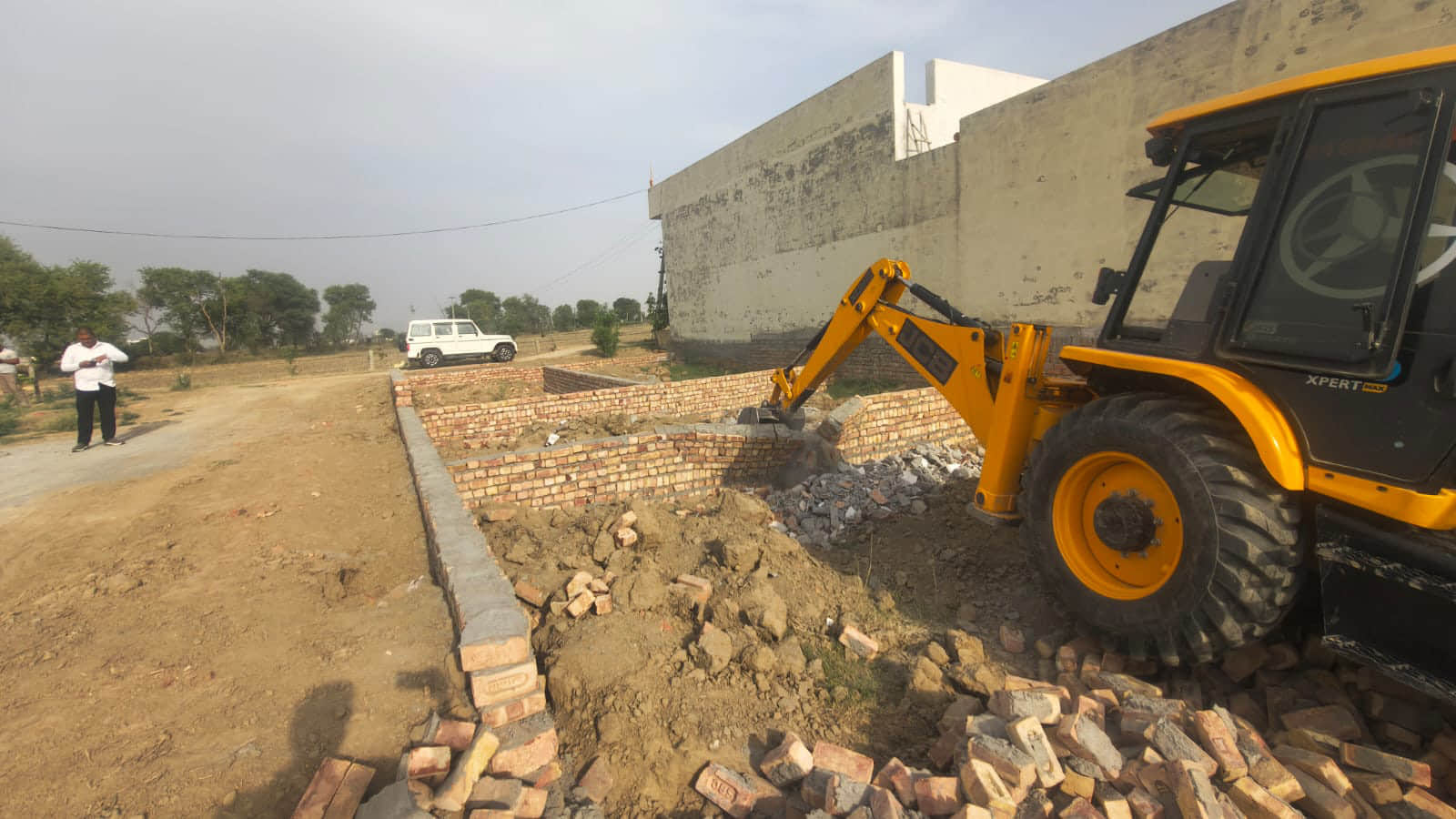 अवैध निर्माण गिराता जेसीबी चालक। डीटीपी