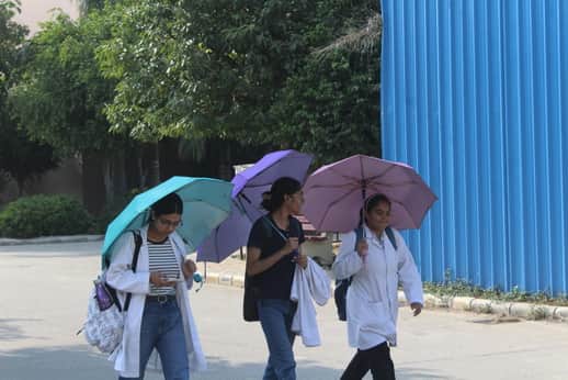 धूप से बचने के लिए छाता लेकर जाती छात्राएं। संवाद