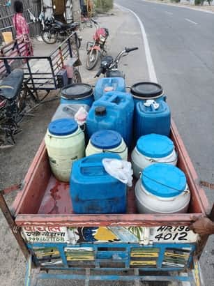 हैंडपंप से पानी भरते हुए लोग।रिक्शा में कैन भरी हुई।