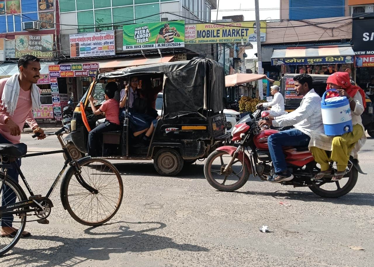 चालक सीट के साथ स्कूली बच्चे को बैठा कर गुजरता ऑटो चालक। 