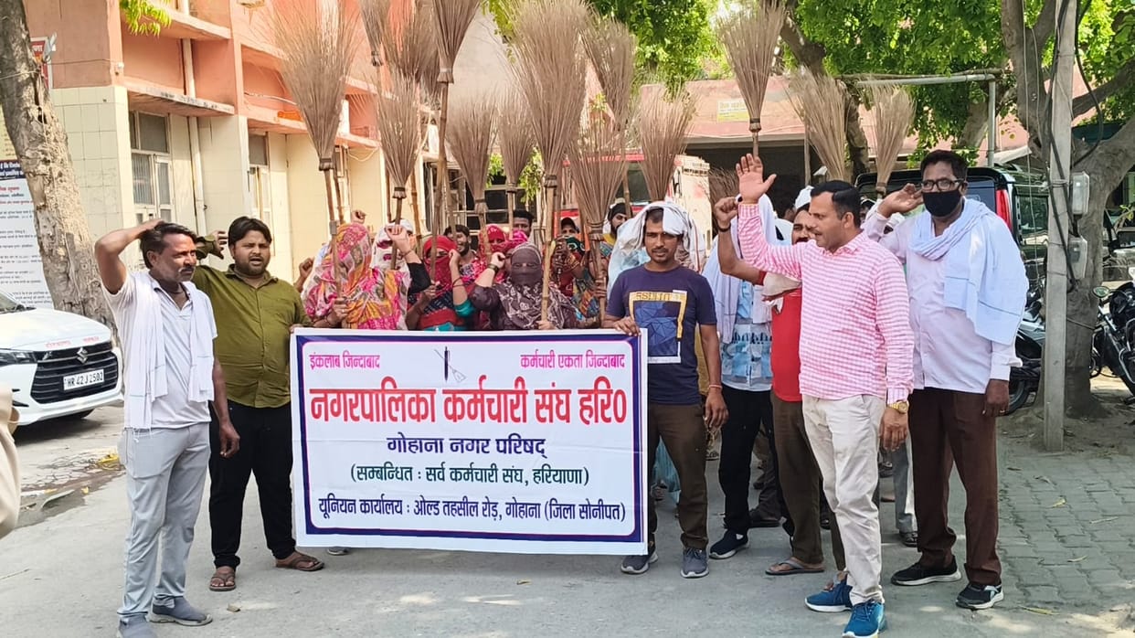Workers protest with brooms, demanding permanent jobs and a salary of Rs 30,000