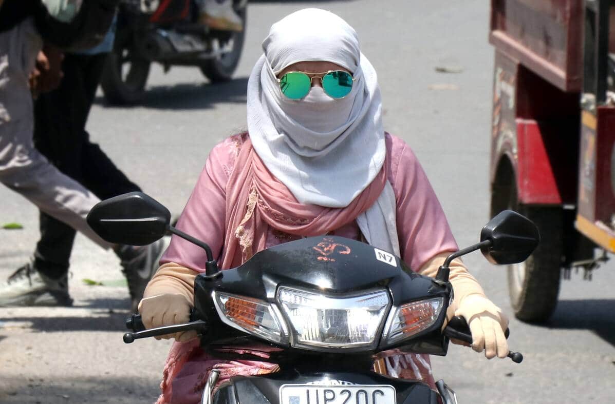 भीषण गर्मी में मुंह पर दुपट्टा बांधकर जाती युवती। संवाद