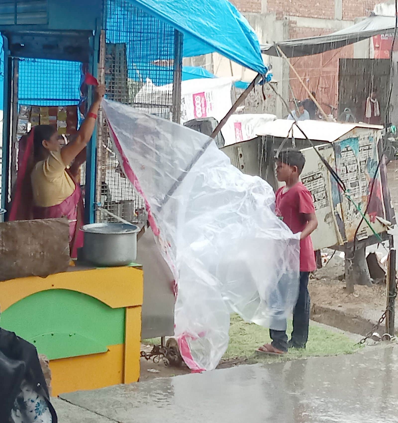 बारिश से बचाने के लिए सामान को ढकते महिला। संवाद