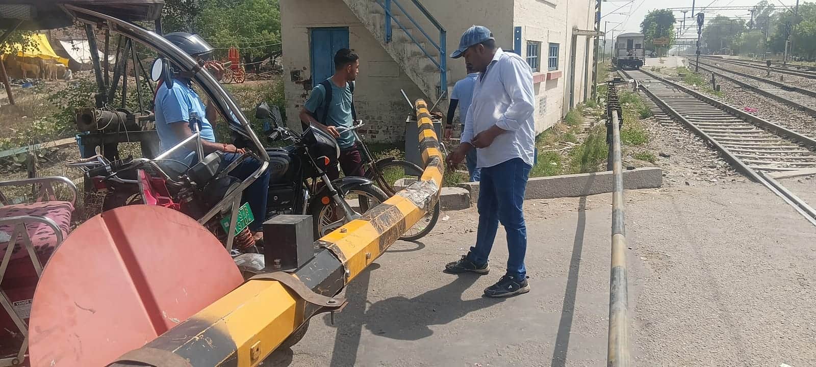 पिलखुवा में रेलवे रोड पर स्वचालित रेलवे बैरियर को सही करता रेलवे कर्मचारी।संवाद