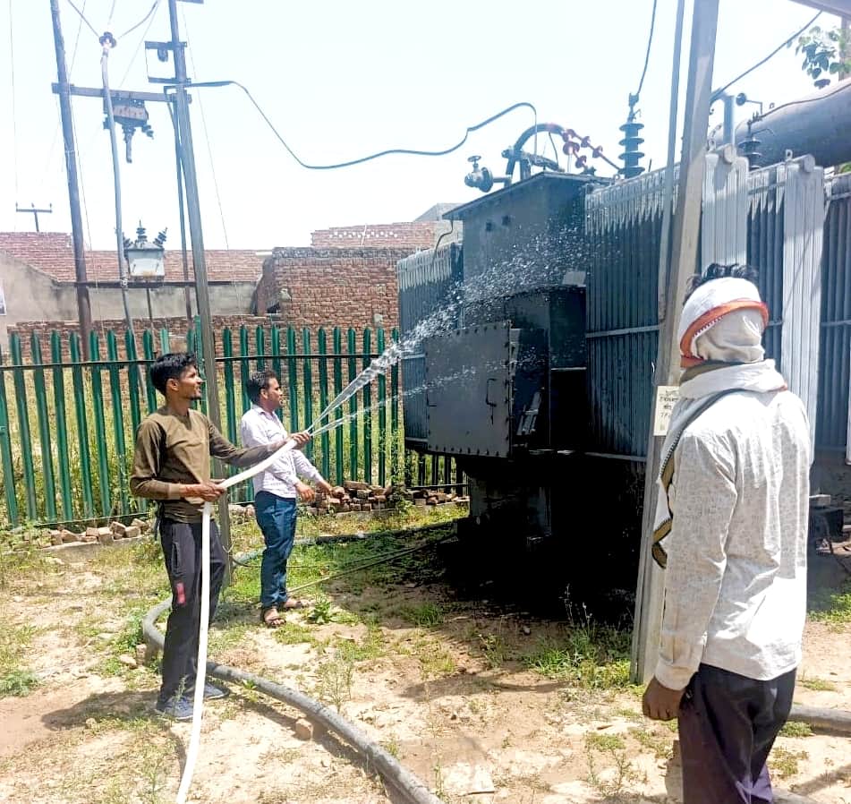 सादाबाद में ट्रांसफॉर्मर पर पानी डालता विद्युत कर्मचारी। स्रोत : विद्युत निगम