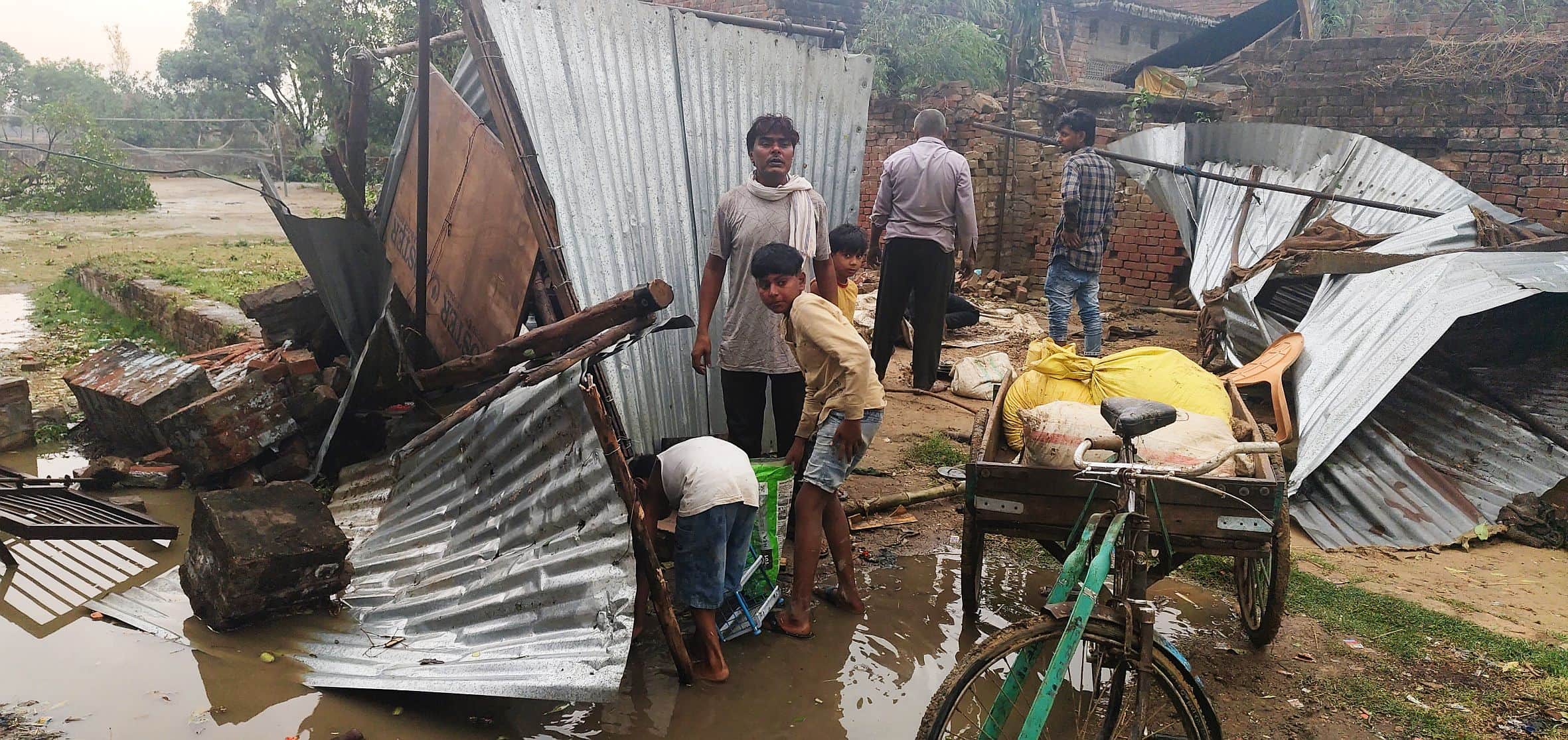 बाजारशुकुल के महोना कस्बे में आंधी से गिरी गुमटी के समान को निकालते लोग।   -संवाद