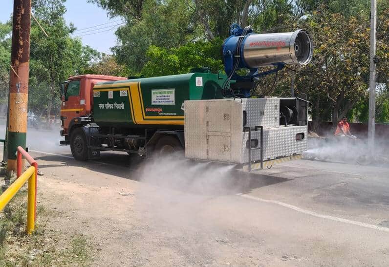 शहर की सड़कों पर पानी का छिड़काव करती नगर परिषद की फव्वारा मशीन।