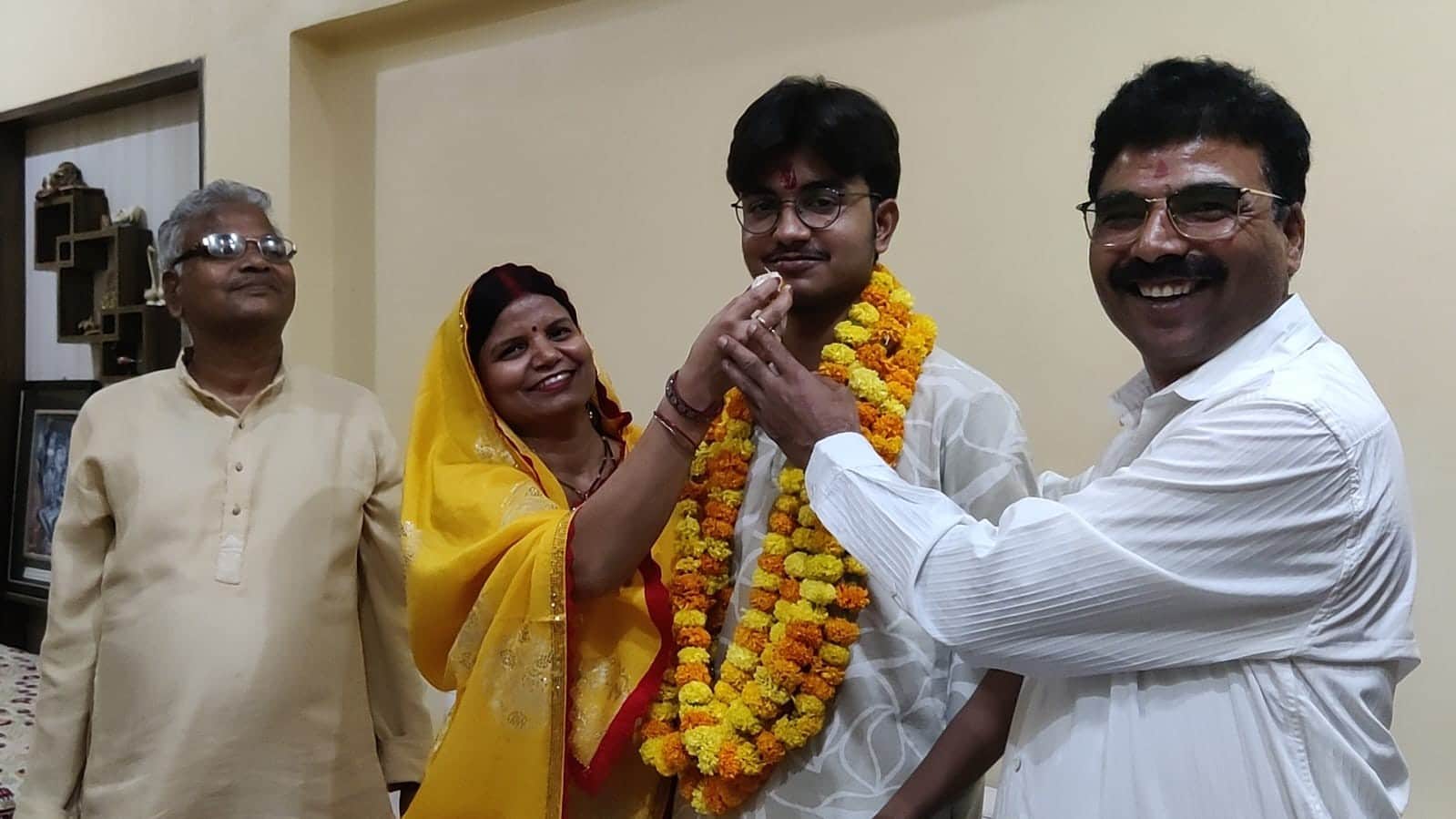 इंटरमीडिएट के टापर नैतिक को मिठाई खिलाते माता-पिता। संवाद