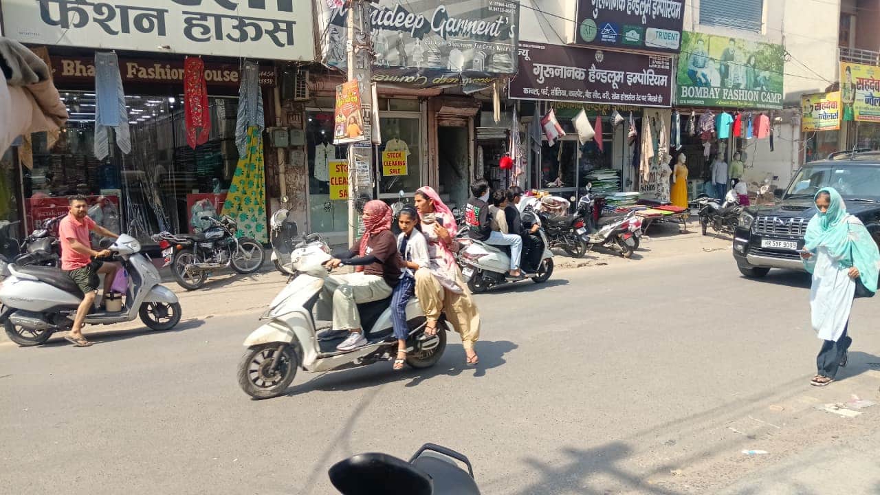 शहर के थाना रोड से गर्मी से बचने के लिए मुहं पर कपड़ा बांधकर जाती स्कूटी सवार महिलाएं। संवाद