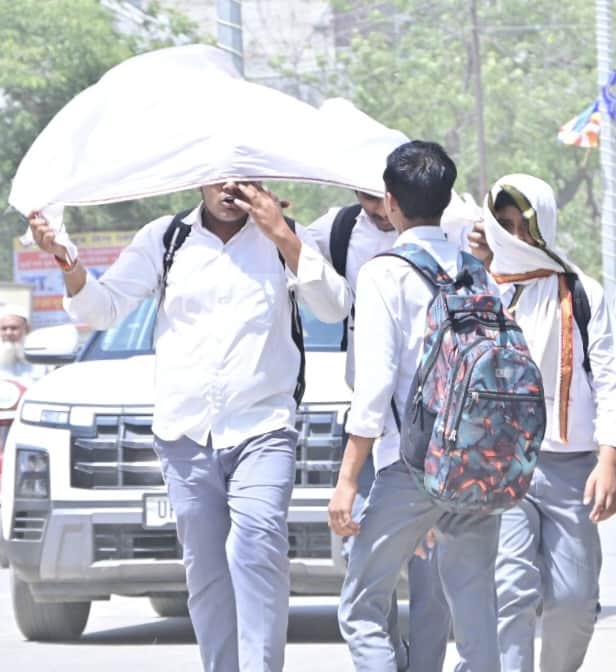 दोपहर की चिलचिलाती धूप में विद्यालय की छुट्टी होने के बाद गमछा से सिर को ढक कर जाते छात्र।