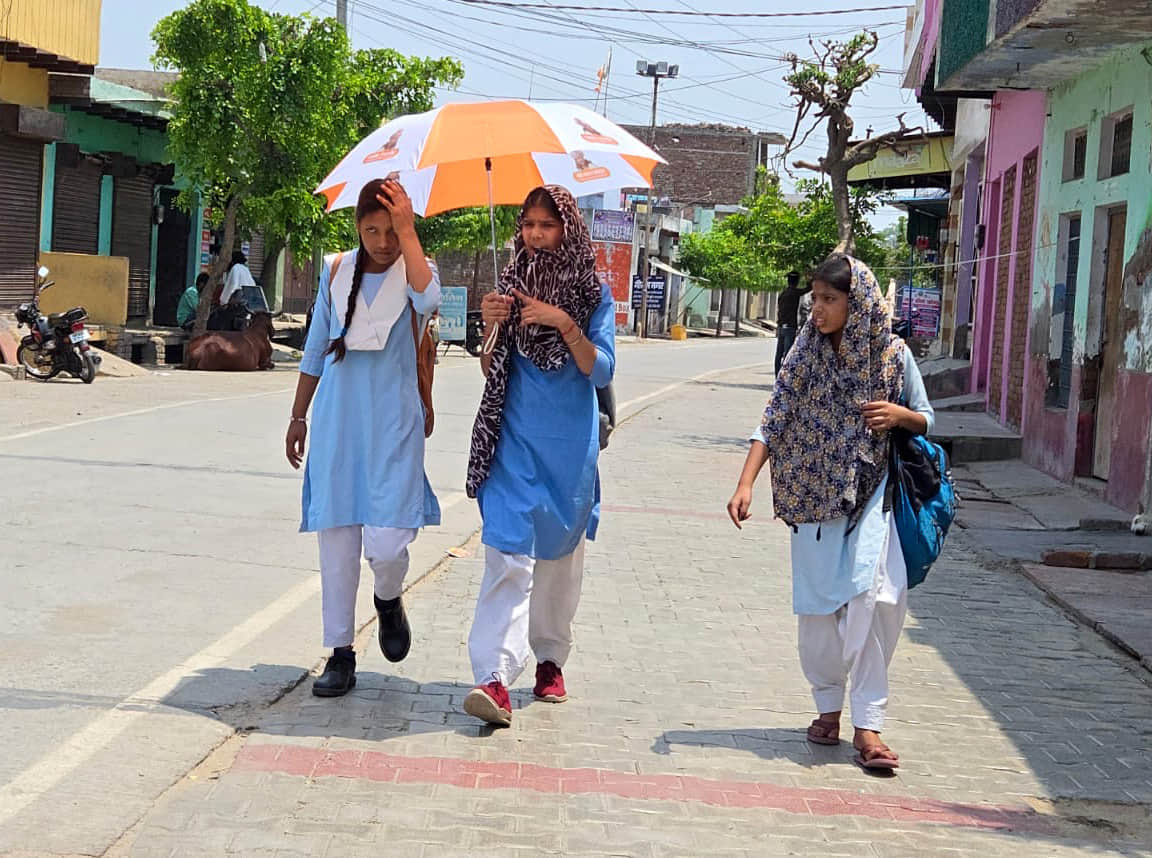 खुर्जा में शनिवार को तेज धूप से बचने के लिए छाता लगाकर जातीं छात्राएं। संवाद