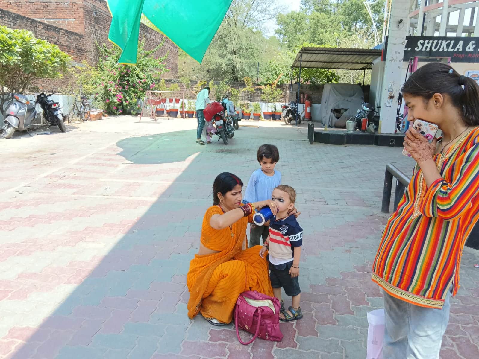 फोटो - 06 बस से उतरकर अपने बच्चे को गर्मी से बचाने के लिए पानी पिलाती महिला। संवाद