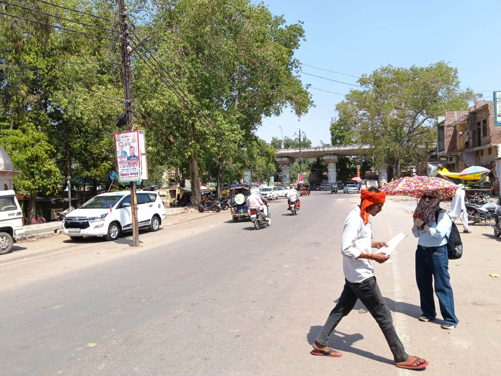 फोटो- 10 झांसी-मिर्जापुर नेशनल हाईवे पर धूप में छाता लगाए खड़ी युवती। संवाद