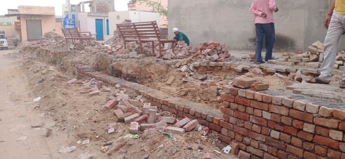 टिया सामग्री का आरोप लगाकर ग्रामीण द्वारा रुकवाया गया चहारदीवारी का काम। 