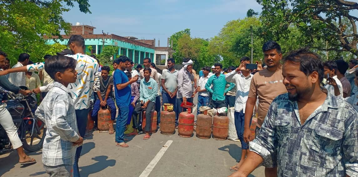 सड़क पर सिलिंडर रखकर प्रदर्शन करते उपभोक्ता।