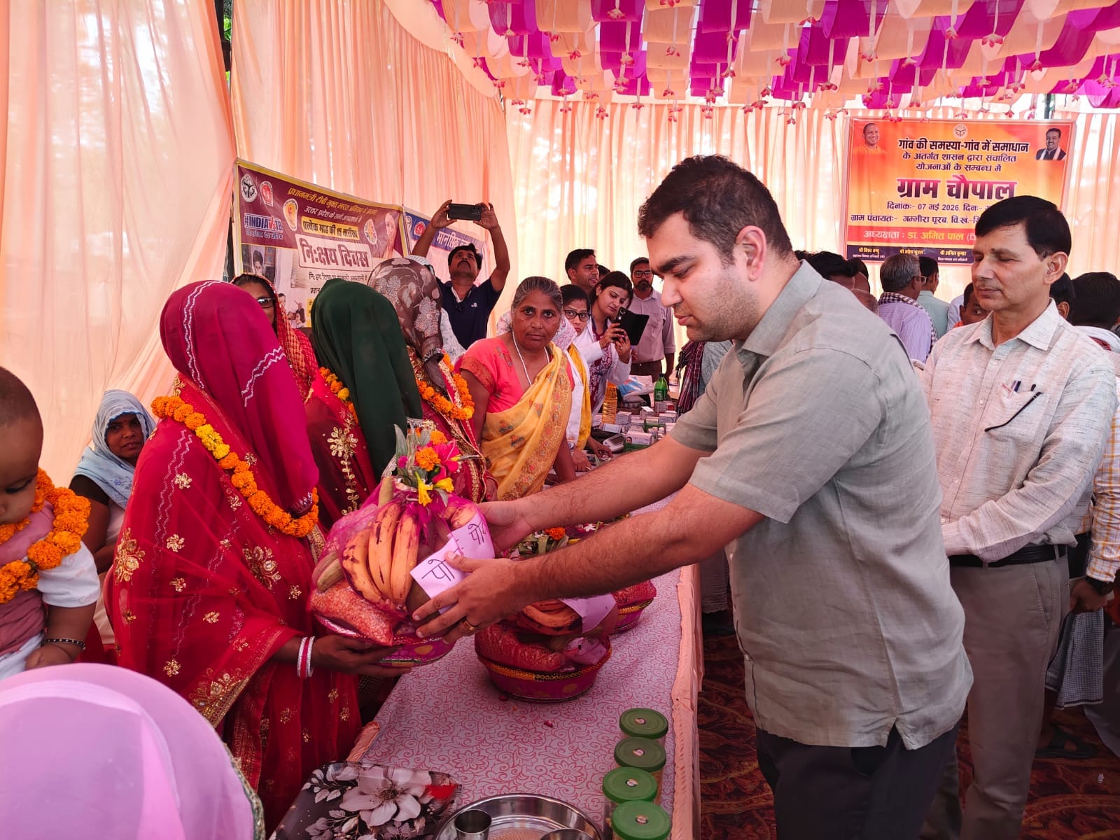 ग्राम चौपाल में गर्भवती महिला को पौष्टिक आहार वितरित करते डीएम डॉ. अमित पाल। स्रोत: प्रशासन