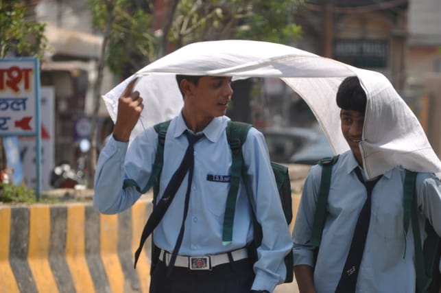 रेलवे रोड पर गर्मी में गमछा ओढ़कर सड़क पर जाते छात्र। संवाद