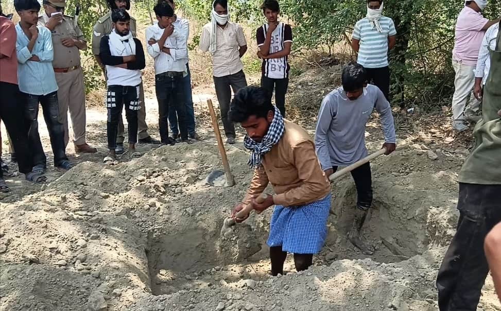 फरिहा के पास स्थित कब्रिस्तान में शव निकालने के लिए कब्र खोदते मजदूर। संवाद