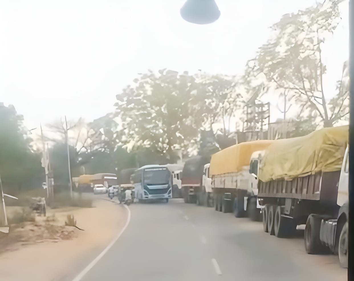 Heavy trucks parked on the roadside are disrupting traffic.