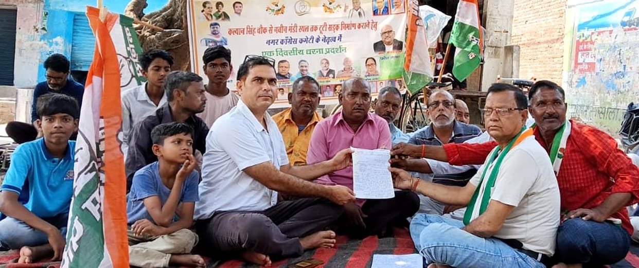 Enraged over delays in road widening, Congress members stage a sit-in protest in the market.