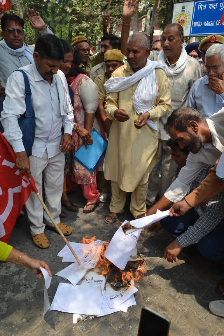  नए नियम कानून की प्रति फूंकते सर्व कर्मचारी संघ के सदस्य। संवाद