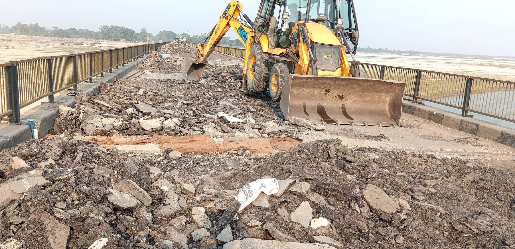 संजय सेतु पर बुलडोजर से खोदी जा रही सड़क की परत।