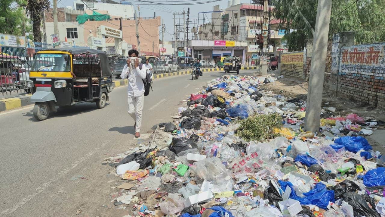 शहर में रोहतक गेट के समीप सड़क  किनारे लगे कचरे के ढेर के पास मुंह पर कपड़ा ढककर जाता युवक।