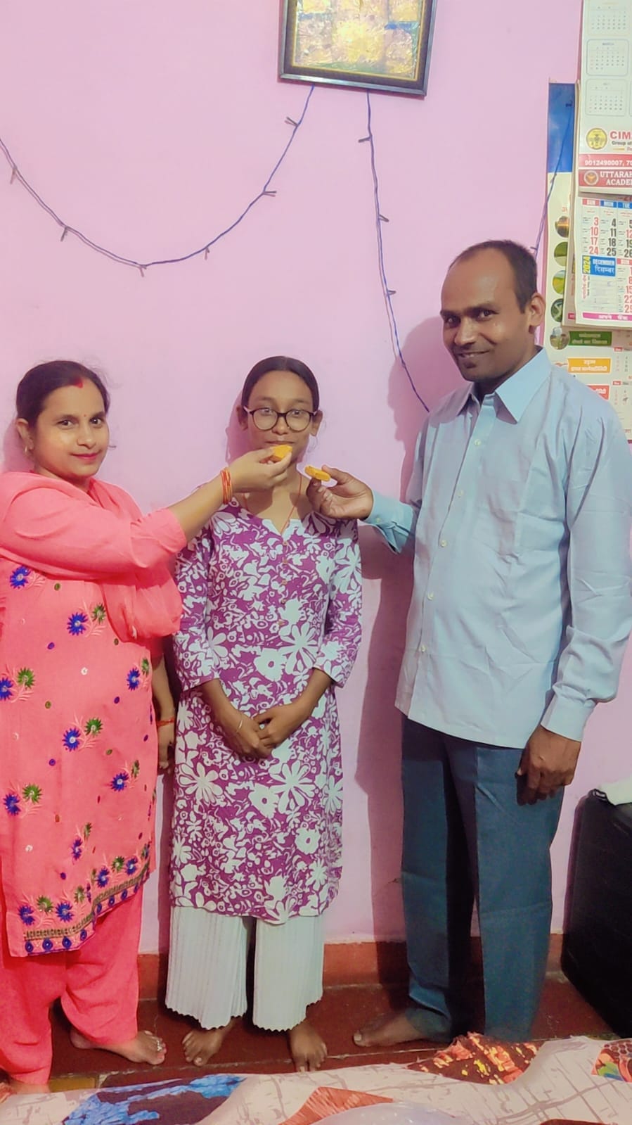ऋषिकेश टॉपर इशिता सिंह को मिठाई खिलाते उनके माता-पिता। स्रोत जागरूक पाठक।