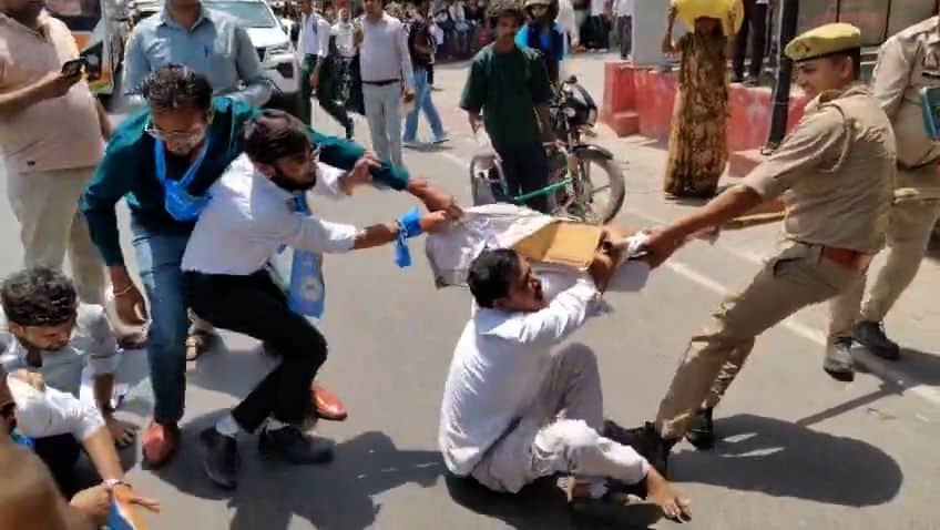 बीएसए रोड पर प्रदर्शन करते एनएसयूआई के कार्यकर्ताओं को हटाता पुलिसकर्मी। 