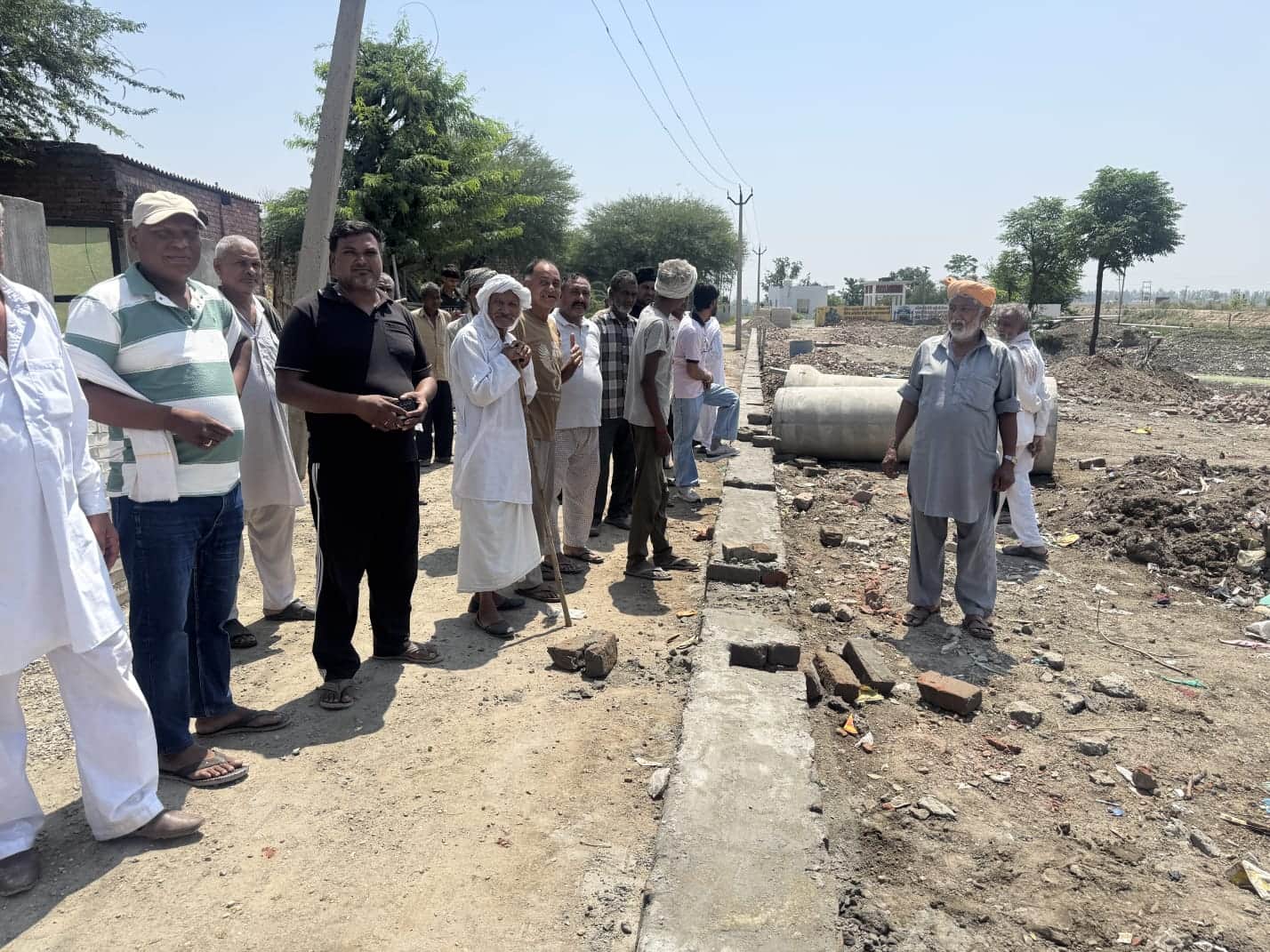 श्मशान घाट के पास दीवार व गली में घटिया सामग्री का विरोध करते ग्रामीण। संवाद