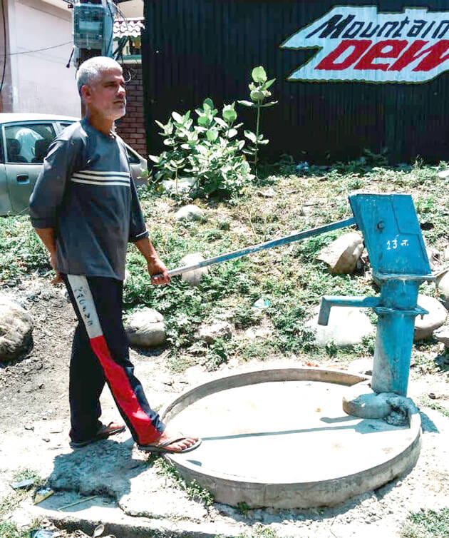 A malfunctioning hand pump poses a problem, with passersby expressing their displeasure