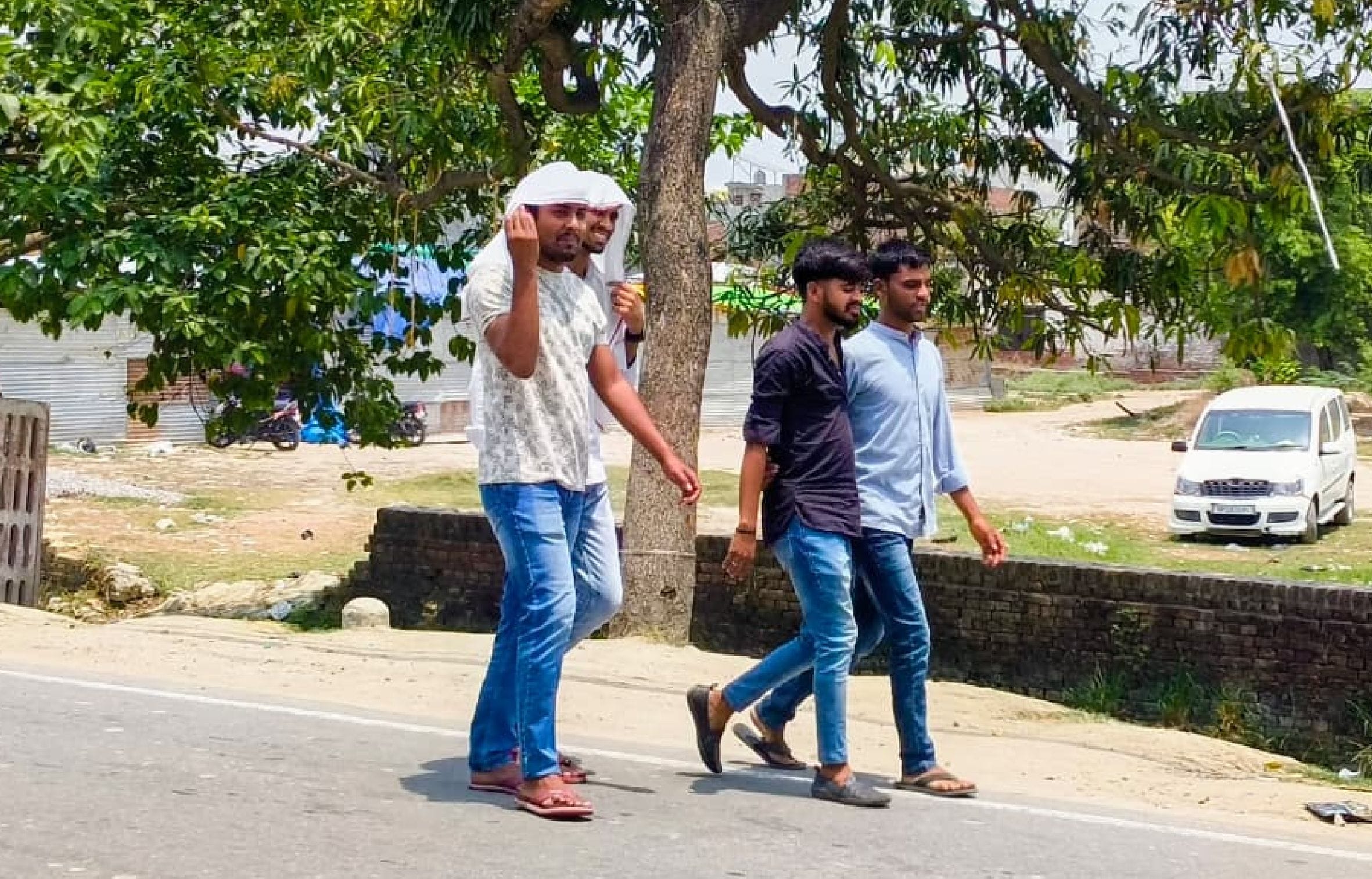  गौरीगंज बाजार में धूप से बचाव के लिए गमछे से सिर ढक कर जाते युवक। -संवाद