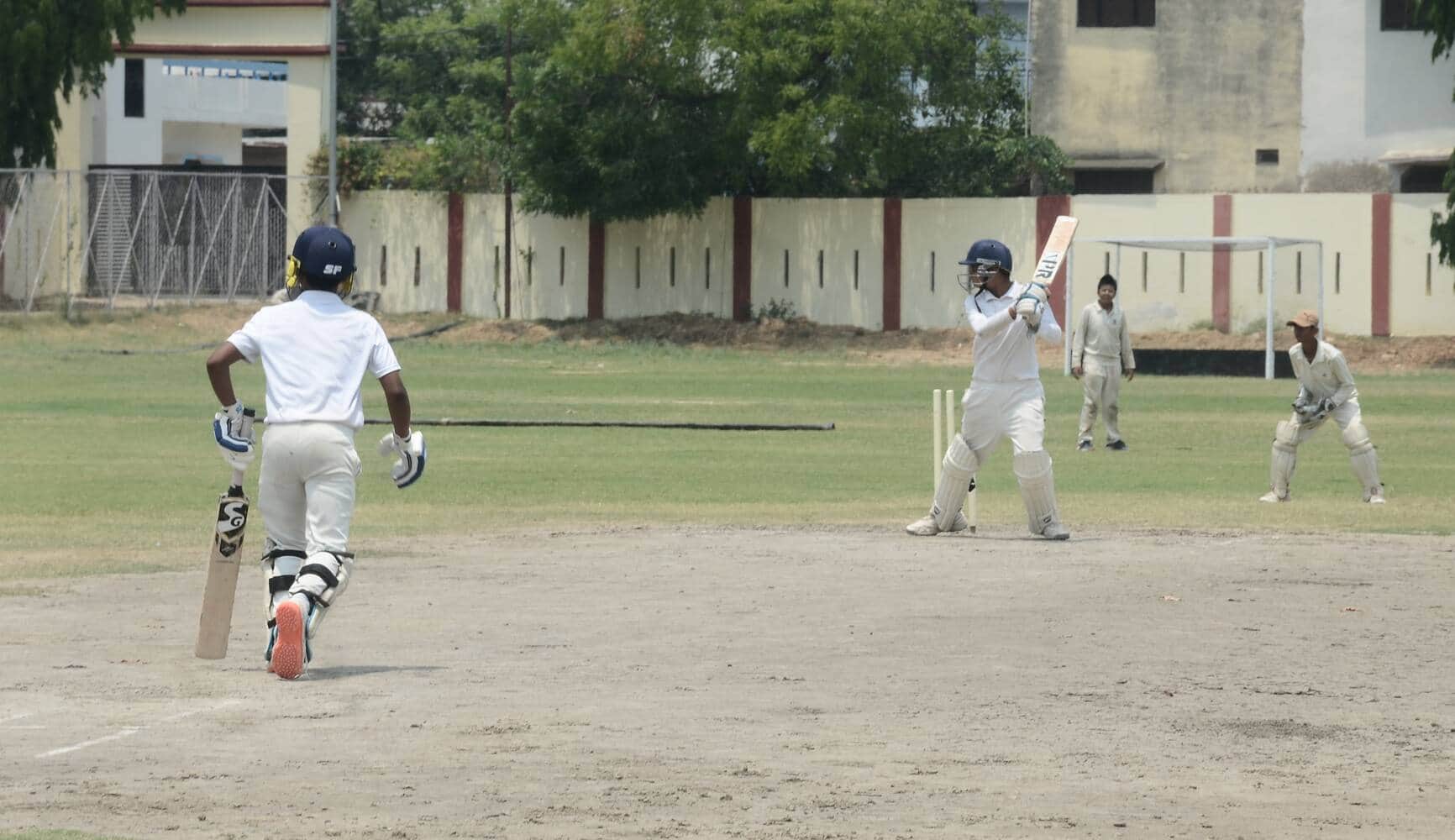 स्टेडियम में आयोजित क्रिकेट मैच खेलते खिलाड़ी। कोच