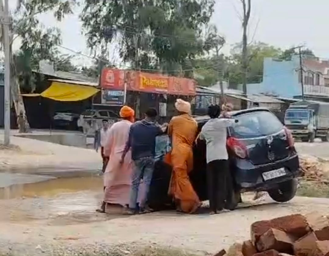 A broken pipeline caused waterlogging on the road, leaving a car stuck in a ditch.