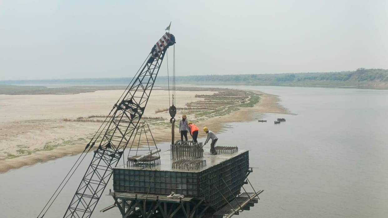 Workers return with safety equipment to the pillar being constructed on the Yamuna River.