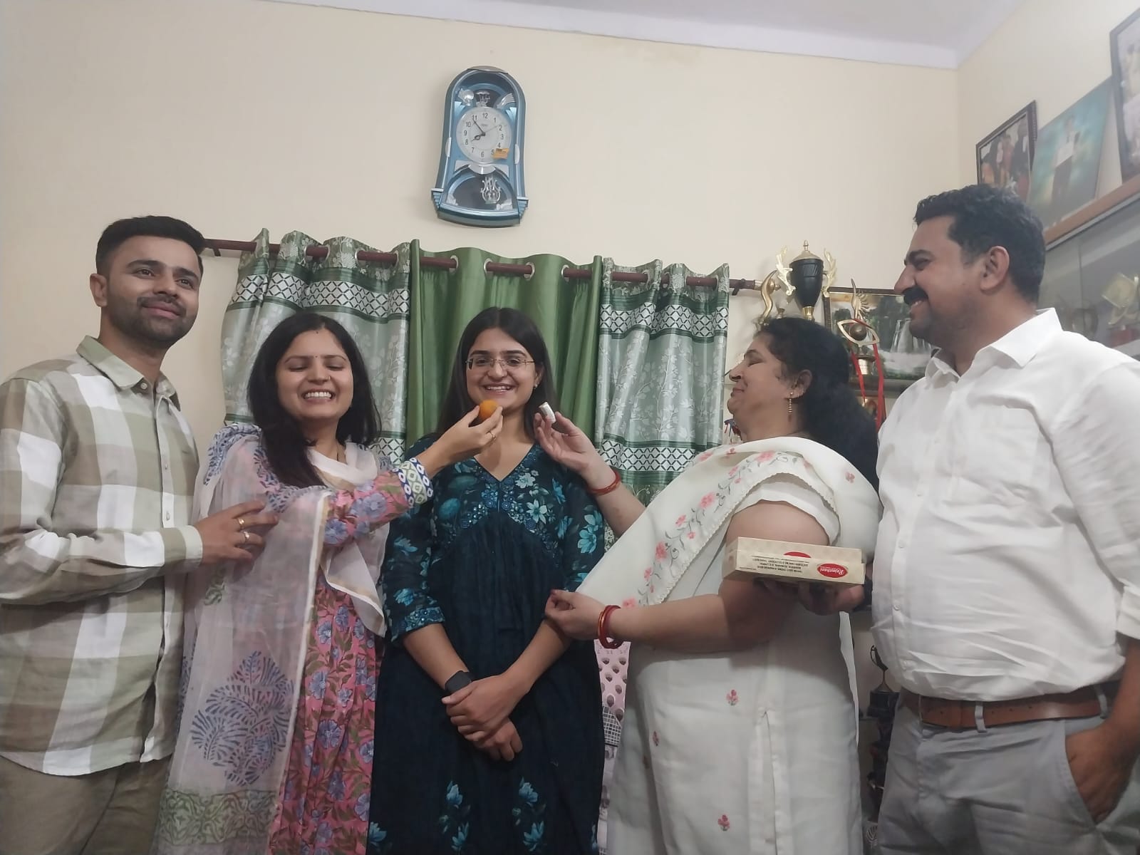 डिप्टी कलेक्टर पद पर चयनित मीनाक्षी भाटियां को मिठाई खिलाते परिजन: संवाद